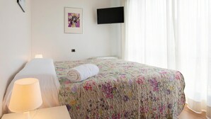 A hotel room with a bed, a bedside lamp, a TV mounted on the wall, and a framed picture.