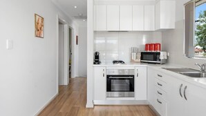 A modern kitchen with white cabinets, a microwave, a coffee maker, and a toaster.