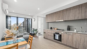 A modern kitchen with wooden cabinets, a built-in oven, and a dining area with a table and chairs.