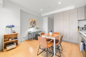 A modern kitchen with a dining area, wooden flooring, and light-colored cabinetry. - Stylish City Home | Rundle Mall at Your Doorstep (Adelaide)