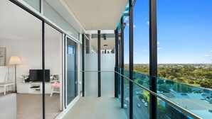 Ein moderner Balkon mit Glastrennwand, einem Flachbildfernseher und einer Sitzecke mit einer Lampe.