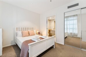 Une chambre à coucher avec un lit, une table de chevet et un miroir.