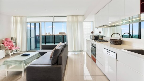 Eine moderne Wohnung mit Wohnbereich, Küchenzeile und großen Fenstern mit Blick auf die Stadt.