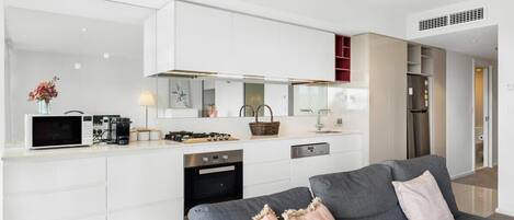 A modern kitchen with white cabinetry, a built-in microwave, and a gas stove.