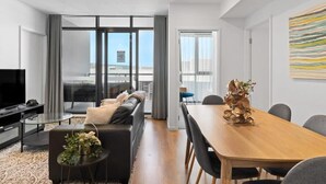A modern living room with a sofa, a coffee table, a TV, and a dining area with a table and chairs.