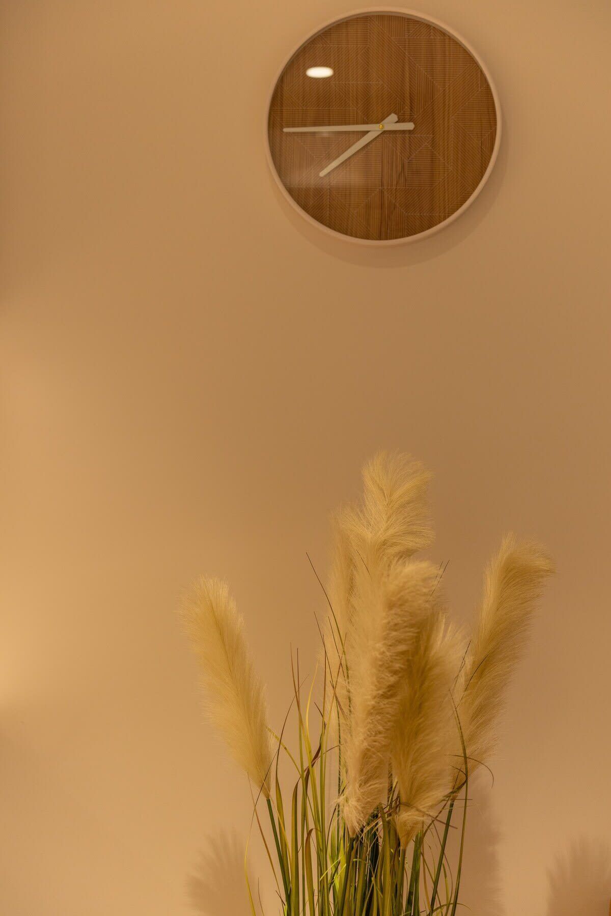 Une horloge murale avec un cadran en bois et une aiguille blanche.