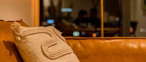 A brown leather sofa with a textured throw pillow.