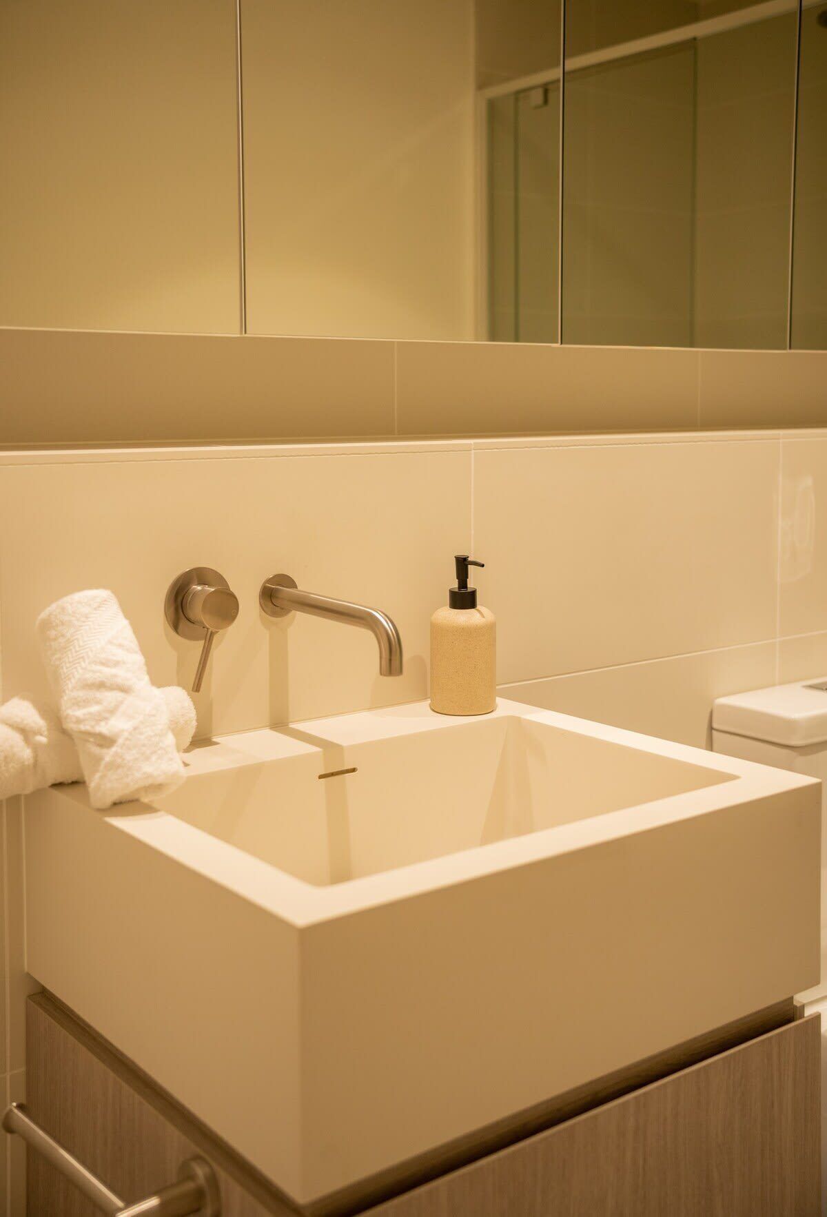Une salle de bain avec un grand lavabo, un porte-serviettes et un distributeur de savon.