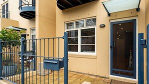 A residential building with a beige exterior, a blue metal gate, and a window with a white frame. - Lego-Aerospace/Free Parking/CBD/Chinatown (Adelaide)