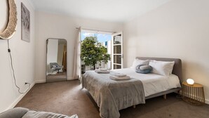 A bedroom with a bed, a bedside table, a mirror, and a view of the outside. - Lego-Aerospace/Free Parking/CBD/Chinatown (Adelaide)