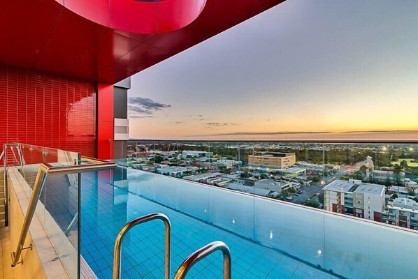 A rooftop infinity pool with a city view at sunset.