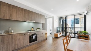 Una cocina moderna con armarios de madera, horno empotrado y comedor con mesa y sillas de madera.