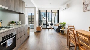 Una cocina moderna con armarios de madera, horno integrado y zona de comedor con mesa y sillas de madera.