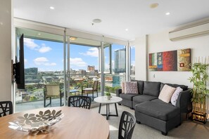 Relax in this stylish living room with a large sofa, floor-to-ceiling doors opening to a balcony with city views, and a flat-screen TV.