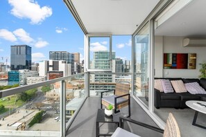 Enjoy a panoramic city view from the large balcony, featuring a comfortable seating area with a sofa set and small table.