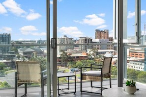 Enjoy a panoramic city view from the comfort of your room, featuring a seating area with two chairs and a small table.