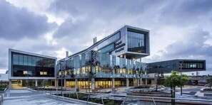 Situated in a landscaped courtyard, this building features a unique architectural design with glass and concrete elements.