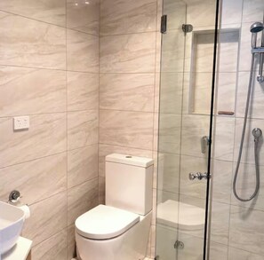 A modern bathroom with a glass-enclosed shower, a toilet, and a sink.