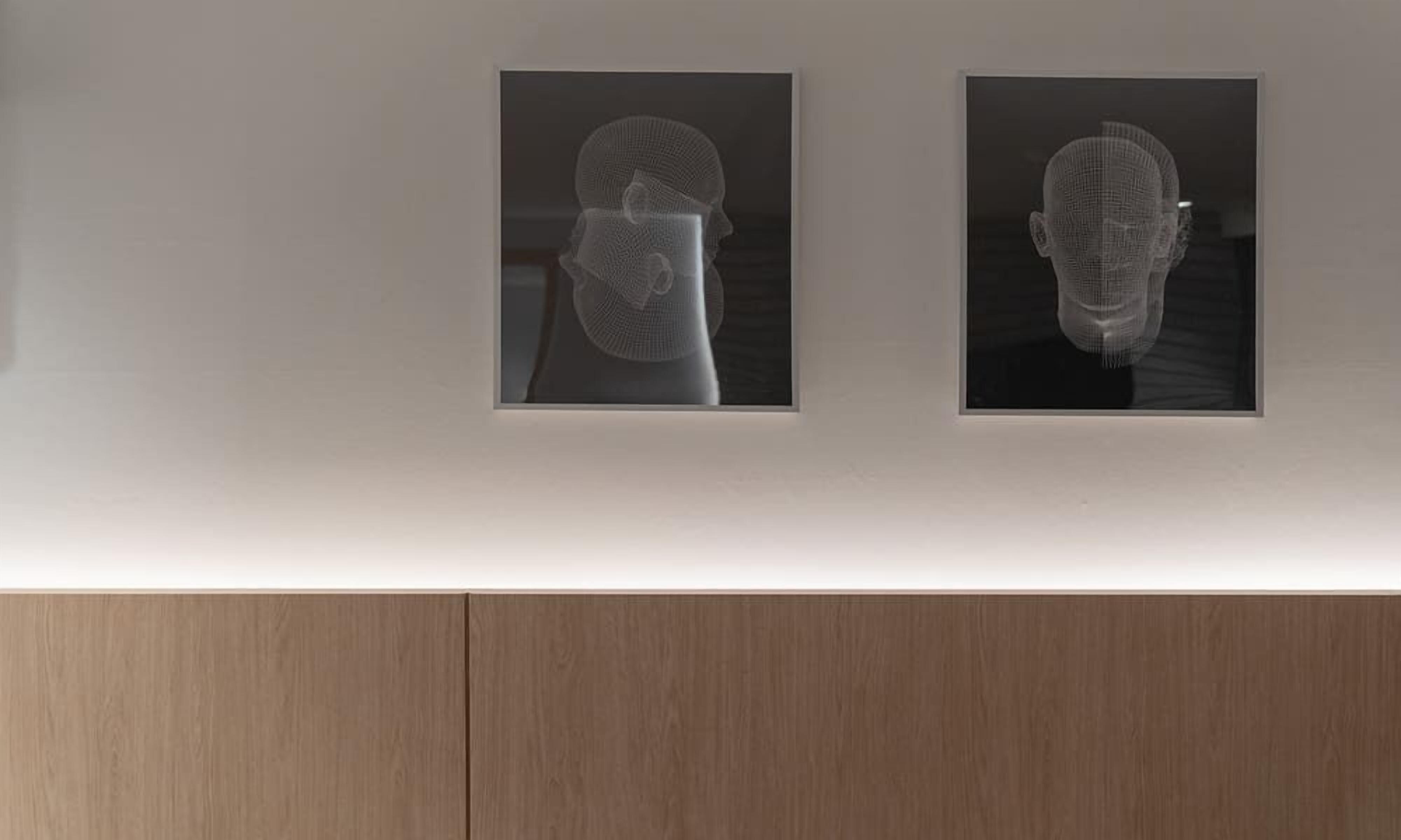 Two framed artworks on a wall, each depicting a human head silhouette.