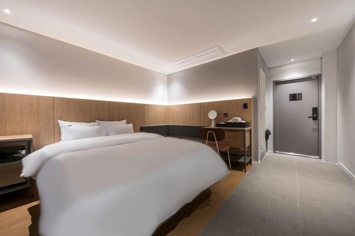 Una habitación de hotel moderna con una cama grande, un escritorio y una puerta.