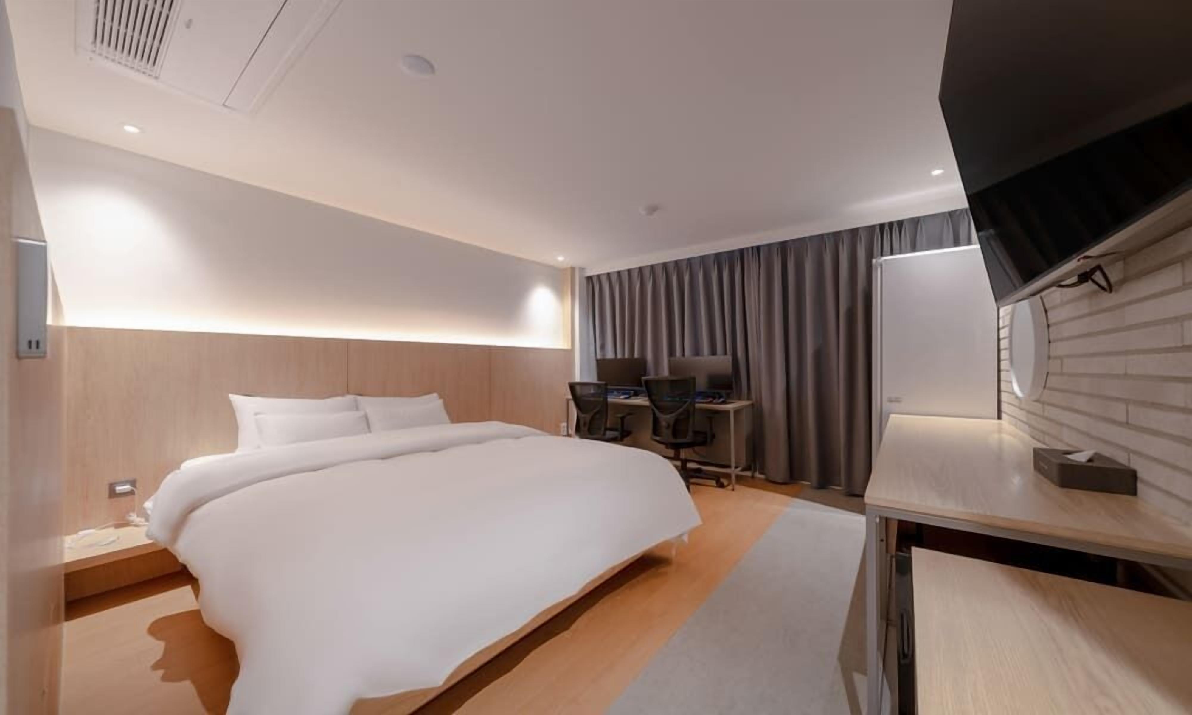Una habitación de hotel moderna con una cama grande, un escritorio y un televisor.