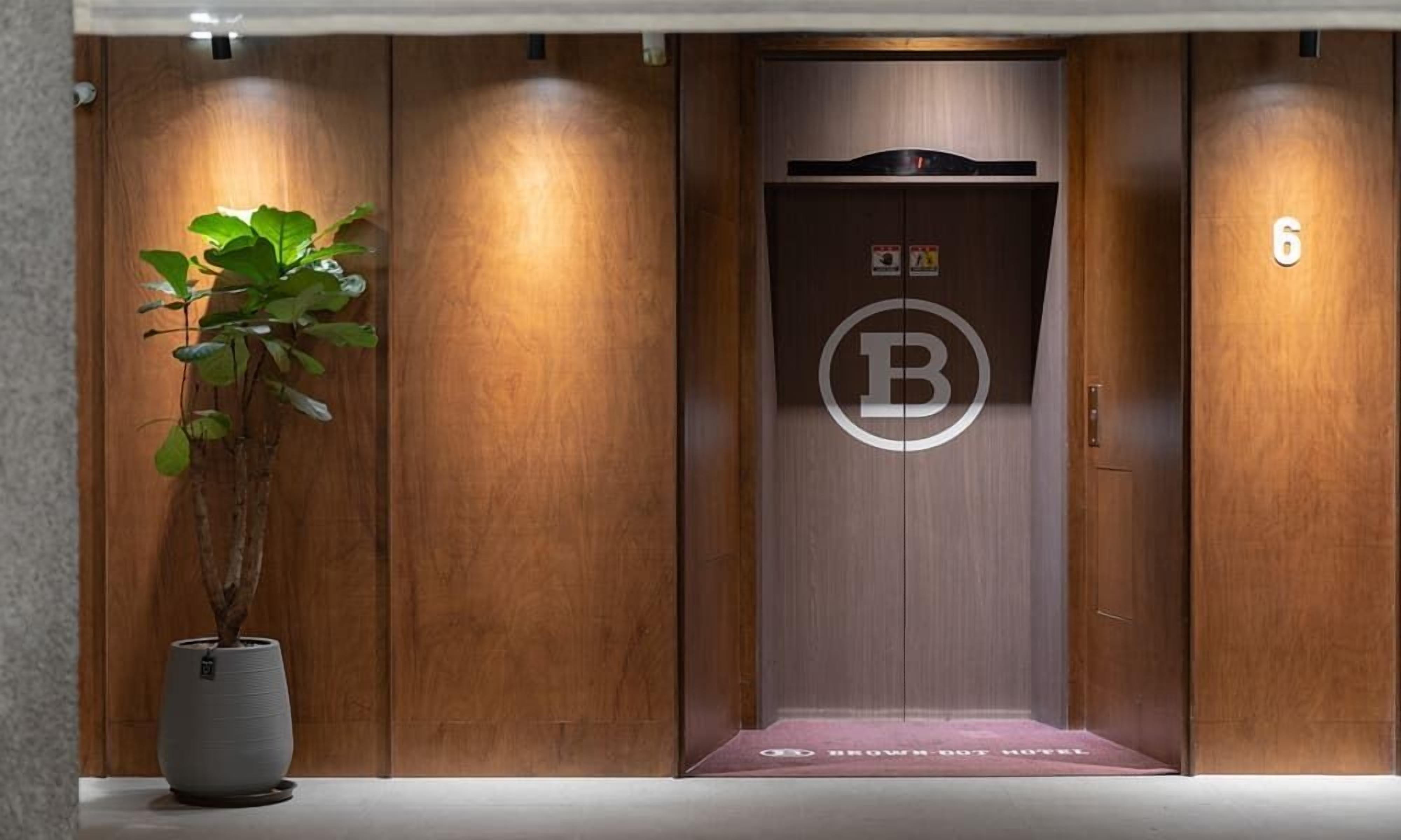 An elevator with a wooden finish, a 'B' logo, and a number '6' on the wall.