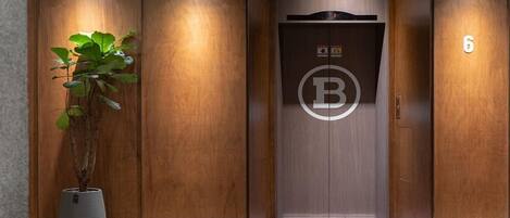 An elevator with a wooden finish, a 'B' logo, and a number '6' on the wall.