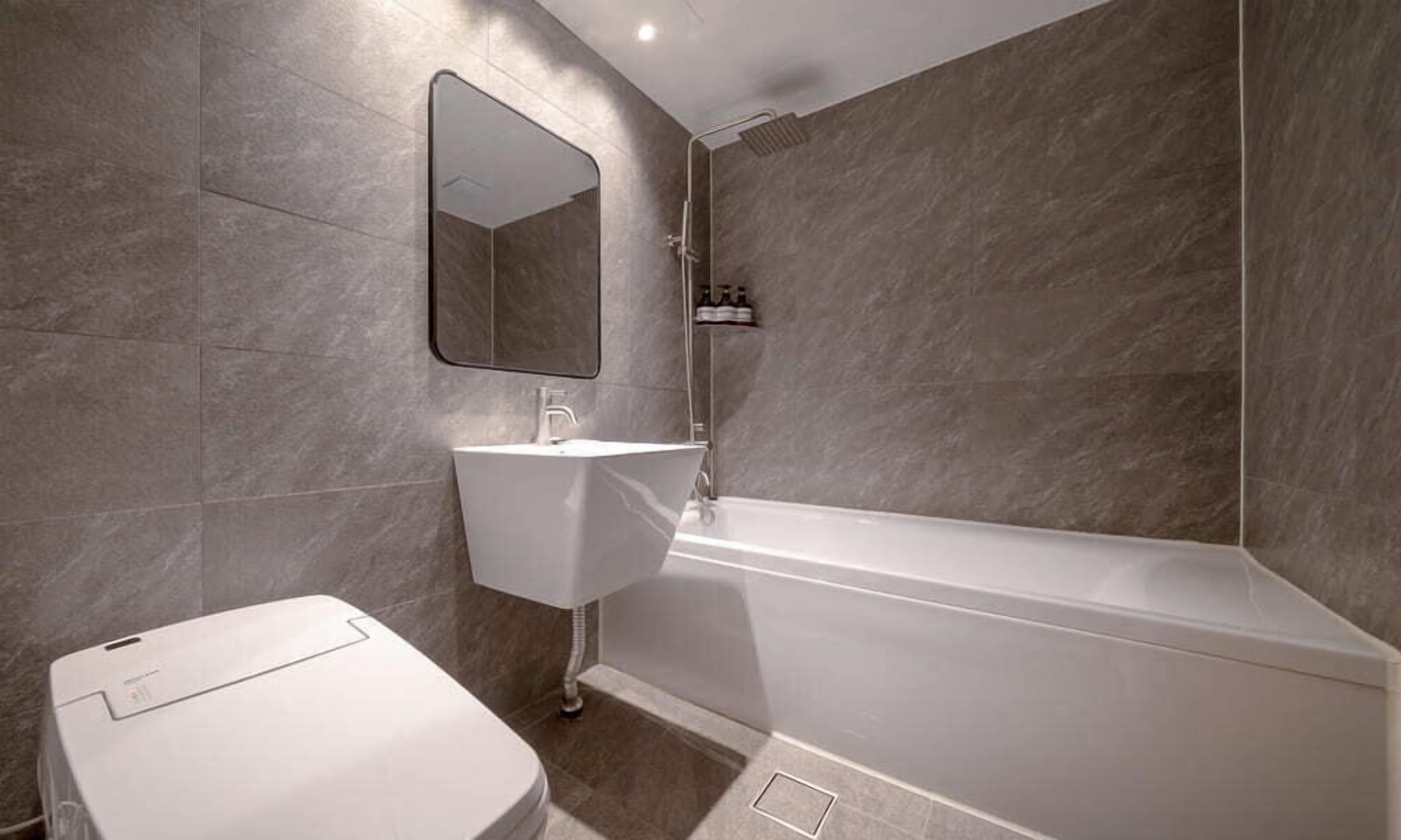 Un baño moderno con una bañera blanca, un lavabo blanco y un inodoro.
