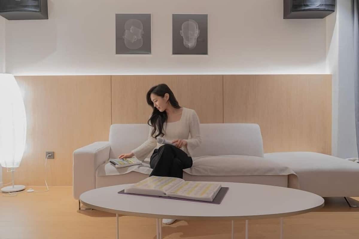 Een moderne woonkamer met een witte bank, een ronde salontafel met een boek, en twee ingelijste foto’s aan de muur.