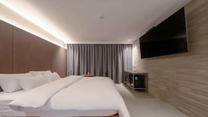 A modern hotel room with a large bed, a flat-screen TV mounted on the wall, and a wooden accent wall. - Siheung Brown Dot Jeongwang (Siheung)