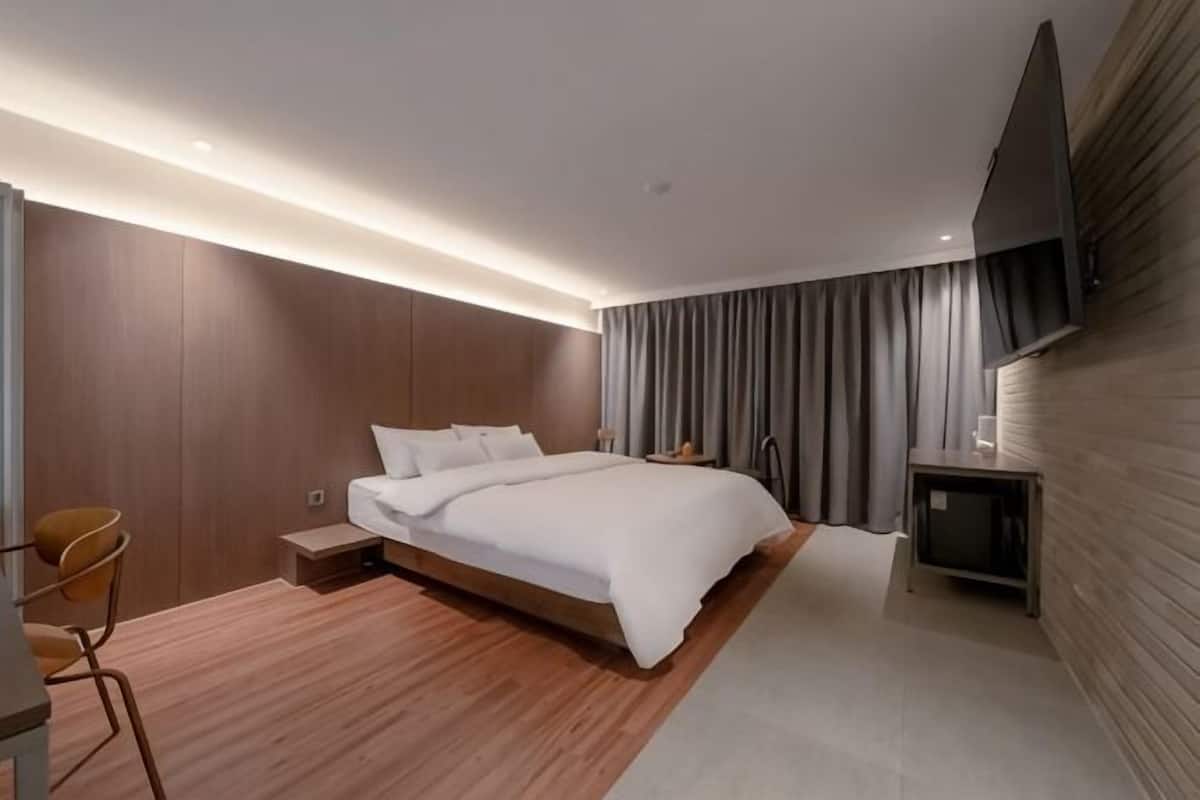 A modern hotel room with a large bed, a desk, and a flat-screen TV.