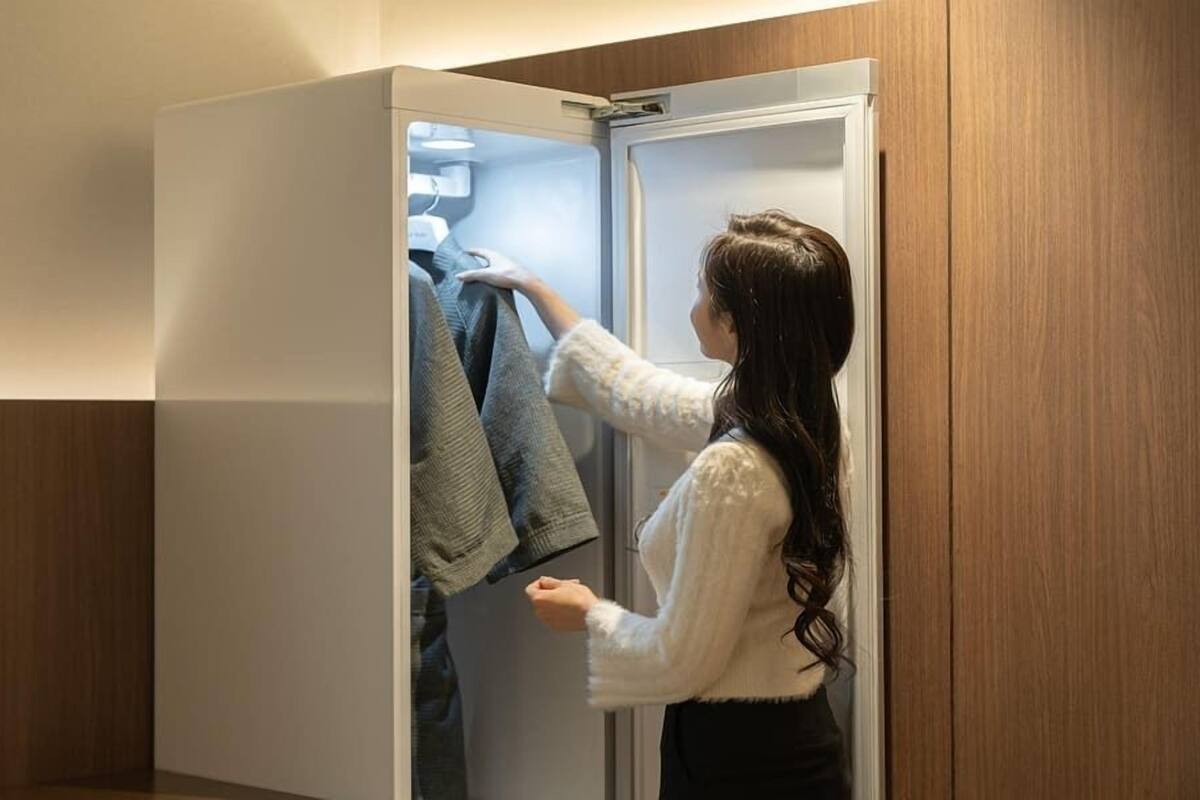 Iemand sorteert kleding in een kast met een spiegeldeur.