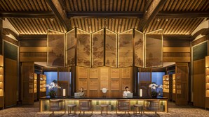 Un área de recepción de diseño tradicional, con un mostrador de madera, tres sillas de madera y un biombo decorativo con obras de arte.