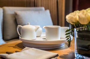 Una bandeja con una tetera, dos tazas y una jarra pequeña sobre una mesa de madera.