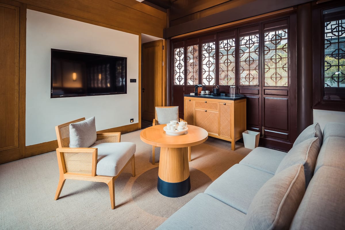 Una habitación de estilo japonés tradicional con suelo de tatami, una mesa de madera baja, un sofá y un armario con un biombo decorativo.