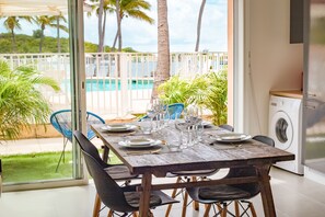 A dining table set for six with chairs, a view of a pool, and a washing machine in the background. - Blue Vista - Paradise in Nettle Bay (Collectivité de Saint-Martin)
