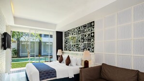 Een hotelkamer met een groot bed, een bruine bank, een behang met patroon en uitzicht op een tuin.