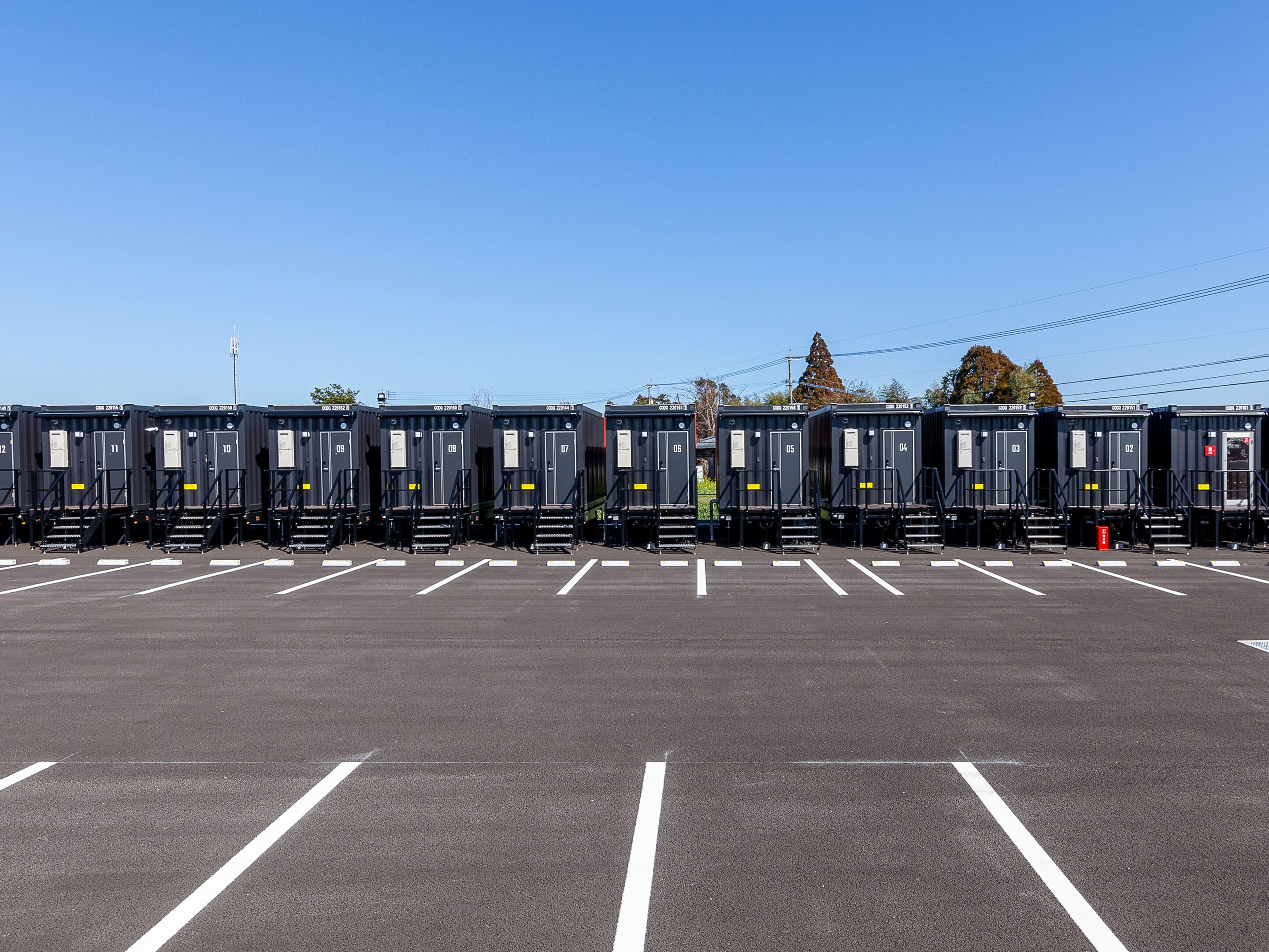 A row of portable restrooms in a parking lot.