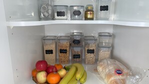 A kitchen pantry with clear storage containers labeled with various food items like sugar, flour, and gluten-free oats. - Peaceful riverfront cottage in tiny northland town (Te Kopuru)