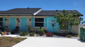 Ein eingeschossiges Haus mit Veranda, zwei Türen und einem kleinen Garten mit verschiedenen Pflanzen.