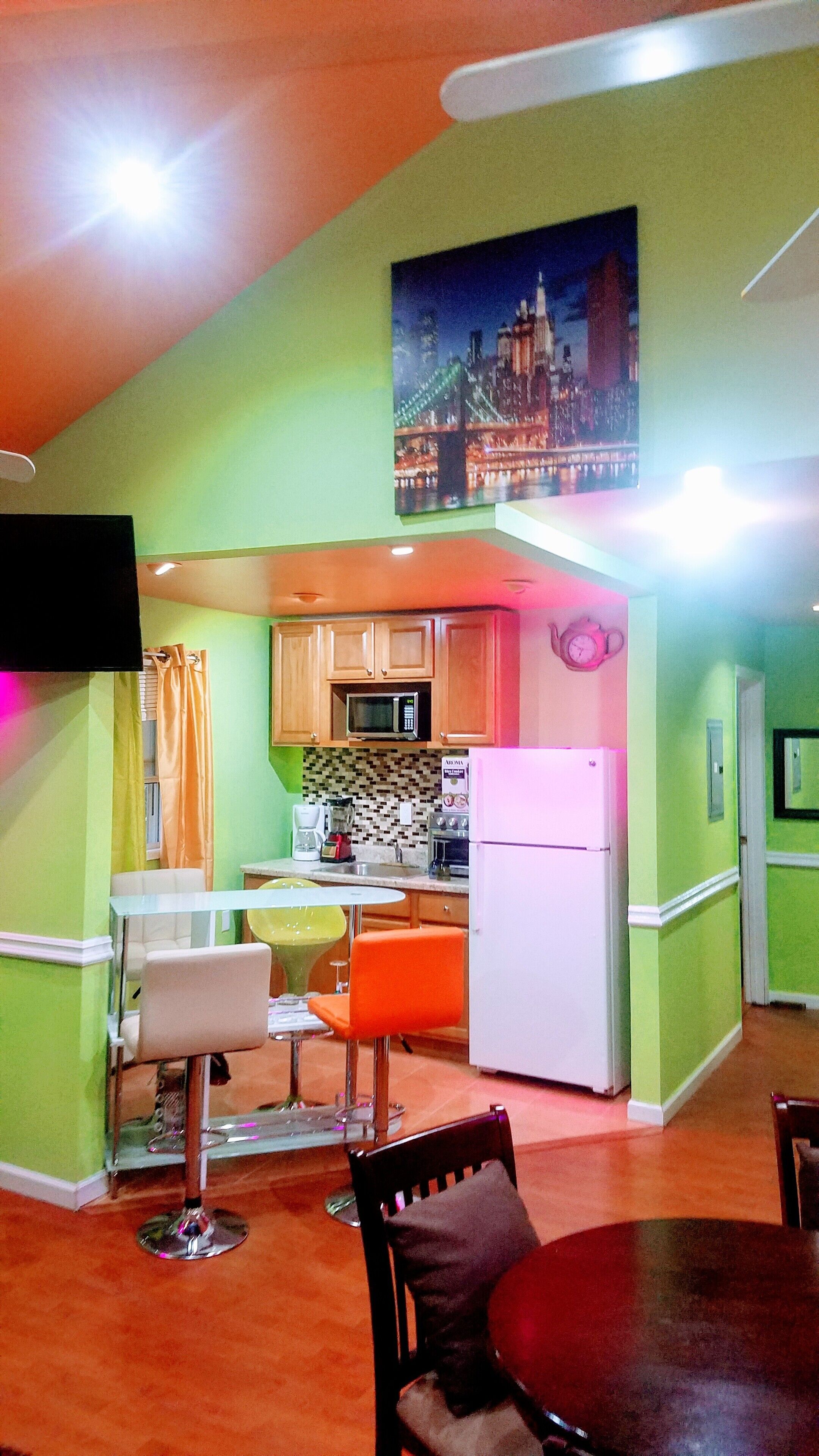 A compact kitchen with a microwave, stove, and refrigerator. There is a dining area with a table and chairs.