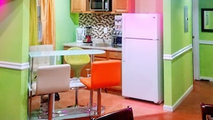 A compact kitchen with a microwave, stove, and refrigerator. There is a dining area with a table and chairs. - Cozydelightful near UBS ARENA, JFK, LAGUARDIA AIRPORT.  (Queens)