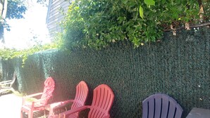 Outdoor seating with chairs and a table, surrounded by a hedge and a building. - Cozydelightful near UBS ARENA, JFK, LAGUARDIA AIRPORT.  (Queens)