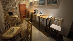 A cozy dining area with stone walls, wooden furniture, and artwork on the walls.
