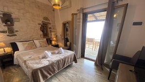 A spacious bedroom with a large bed, a desk, and a view of the outdoor patio.