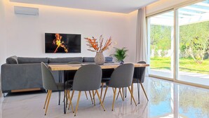 A modern dining area with a grey sofa, a wooden table, and grey chairs. - Fence off , surrounded by large olive grove 200m from the sandy beach (Ζάκυνθος)