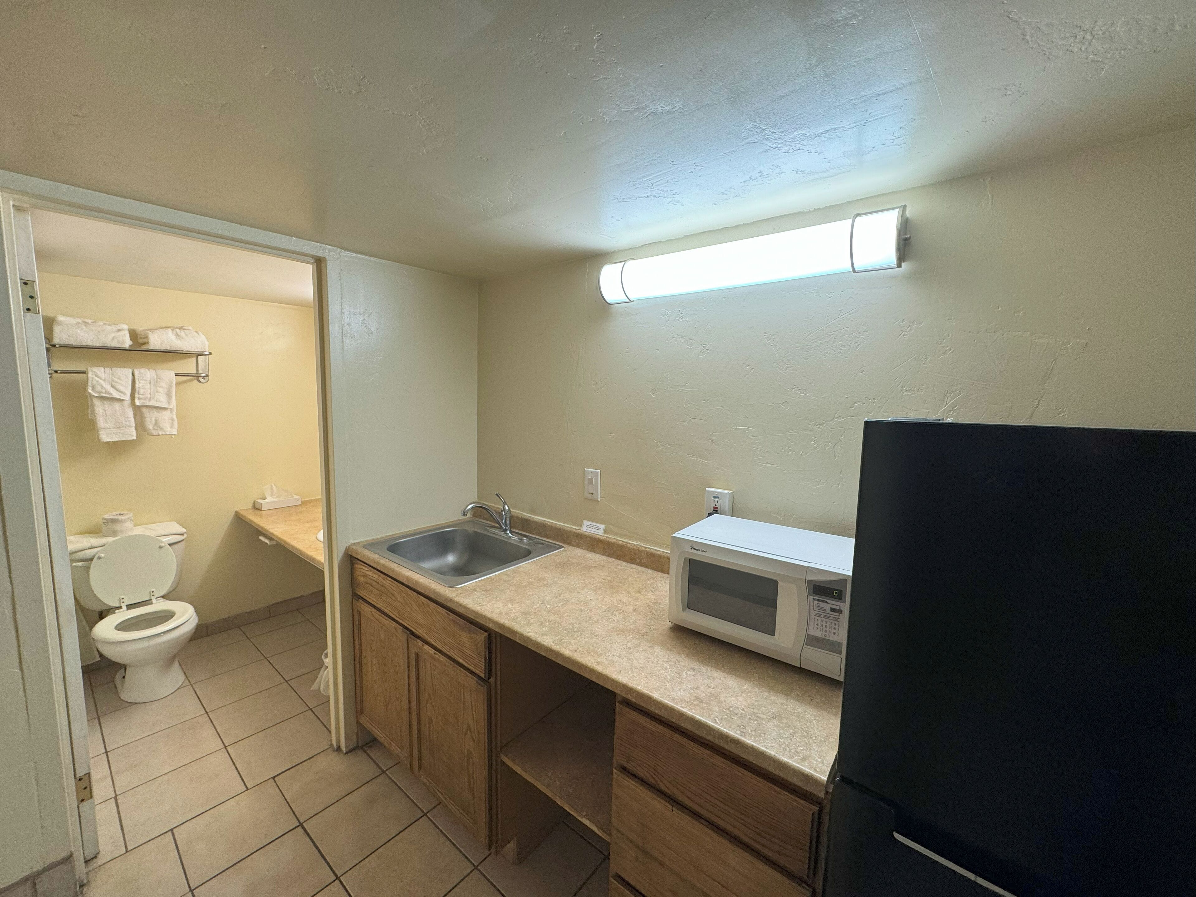 A small kitchenette with a microwave, sink, and cabinets.
