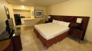 A hotel room with a bed, a desk, a chair, a TV, a refrigerator, a microwave, a sink, and a framed picture on the wall. - Big Chile Inn & Suites (Las Cruces)
