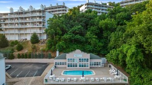Ett hotell med en swimmingpool, flera balkonger och frodig grönska runt om.