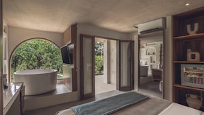 A modern bedroom with a large bed, a built-in bathtub, and a view of lush greenery. - Suara Alam Suite Ubud by Ini Vie Hospitality (Ubud)
